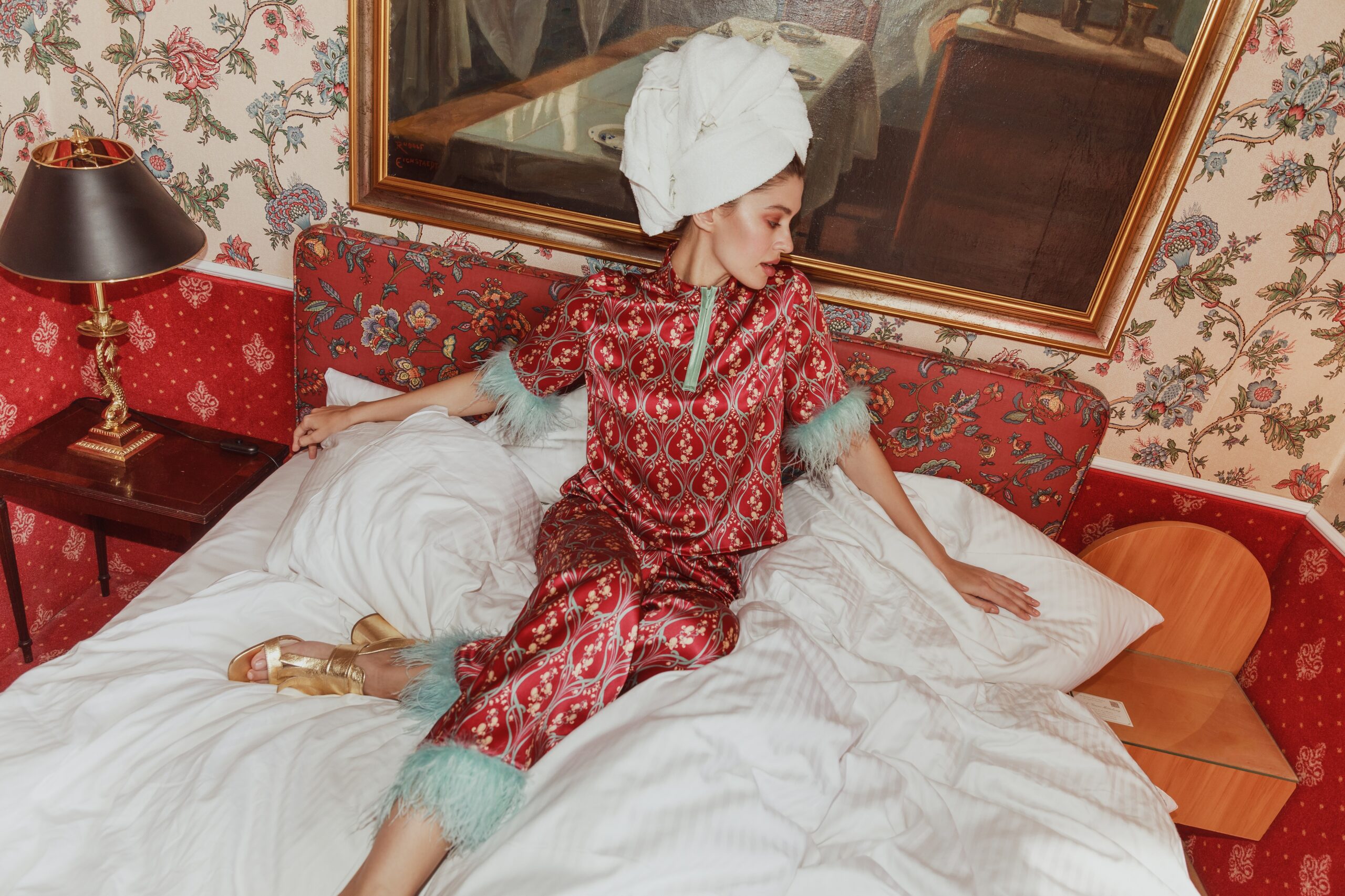 Frau mit Handtuch auf dem Bett im Kleid mit Highheels