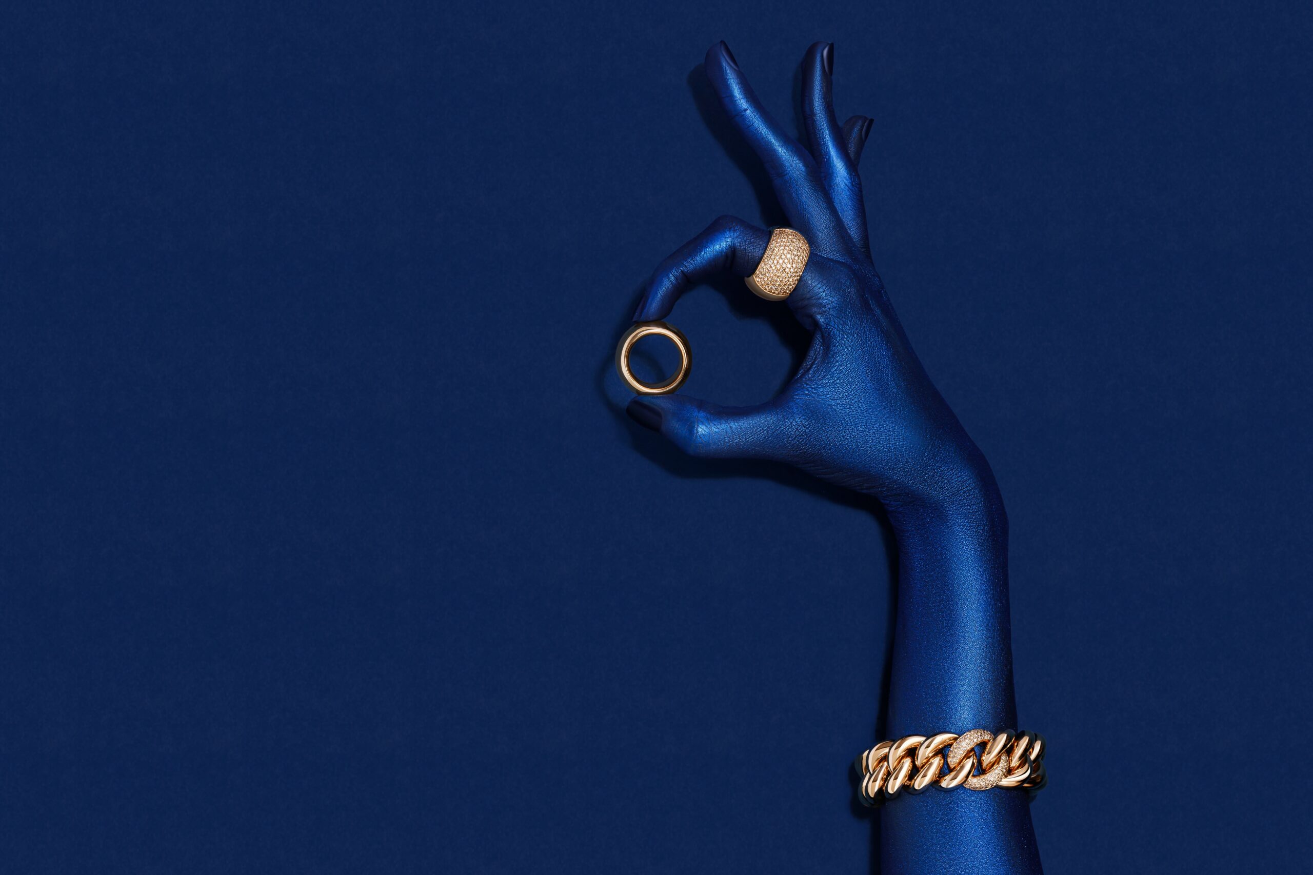 Blaue Hand mit goldenen Ringen und goldenem Armband