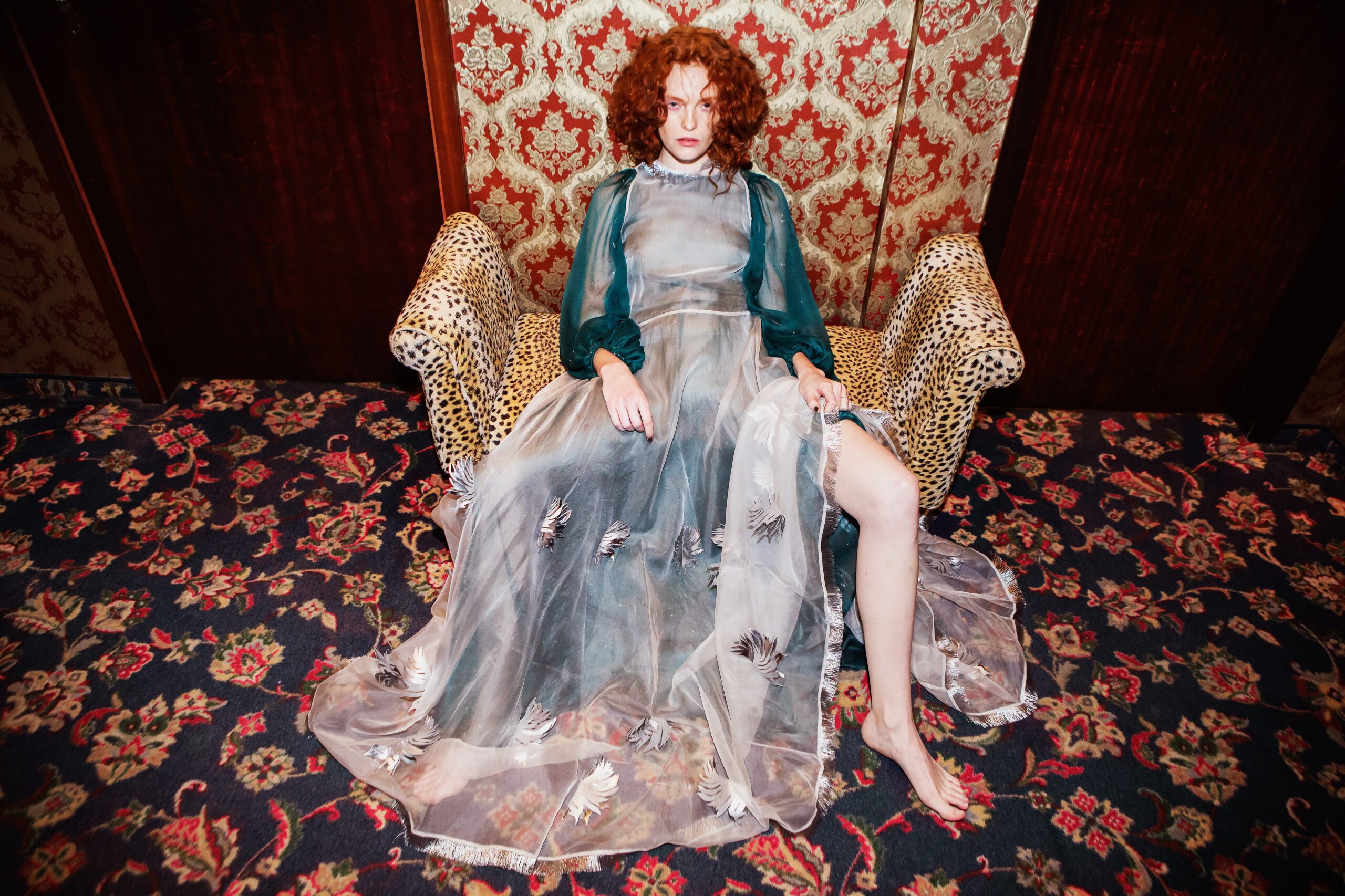 Frau mit Kleid auf einem Sessel mit vielen Mustern
